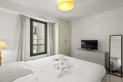 a white bedroom with a white bed and a television at Cannes Croisette 2 bedrooms - 7C3 in Cannes