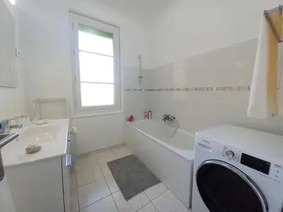 a white bathroom with a tub and a washing machine at Palais Alexandre in Cannes