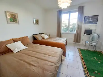 a bedroom with two beds and a couch and a window at Palais Alexandre in Cannes
