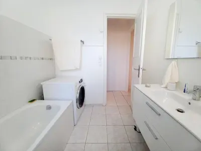 a white bathroom with a tub and a washing machine at Palais Alexandre in Cannes