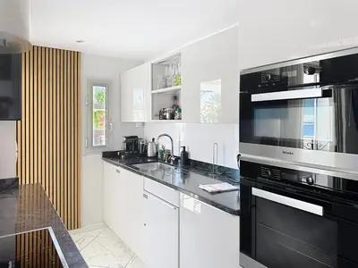 a kitchen with white cabinets and black appliances at Stylish 1-bedroom apartment with sea view on La Croisette in Cannes