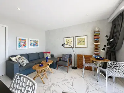 a living room with a blue couch and chairs at Stylish 1-bedroom apartment with sea view on La Croisette in Cannes