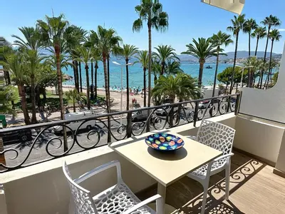 a balcony with a table and chairs and a view of the beach at Stylish 1-bedroom apartment with sea view on La Croisette in Cannes