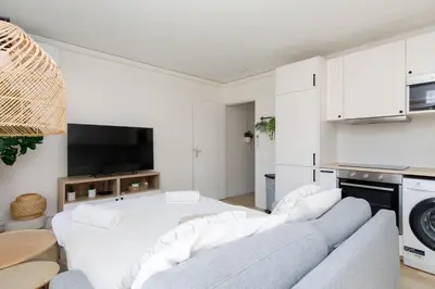 a white living room with white chairs and a table at Immogroom - Warm T2 - AC - Wifi - Comfort in Cannes