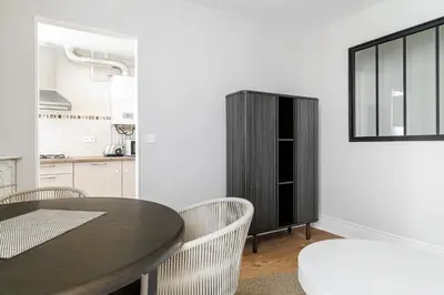 a kitchen with a black cabinet and a table and chairs at L'Escapade Cannoise Forville in Cannes