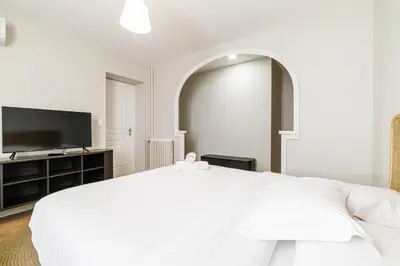 a white bedroom with a bed and a flat screen tv at L'Escapade Cannoise Forville in Cannes