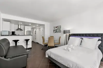 a bedroom with a bed and a chair and a kitchen at Luxury Studio YourHostHelper in Cannes