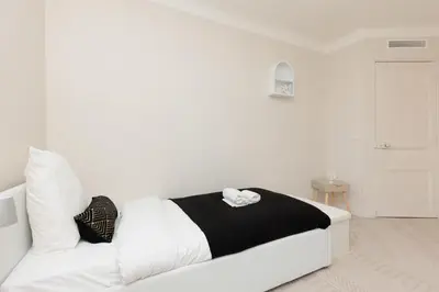 a white bed with black and white pillows in a room at Perrissol YourHostHelper in Cannes
