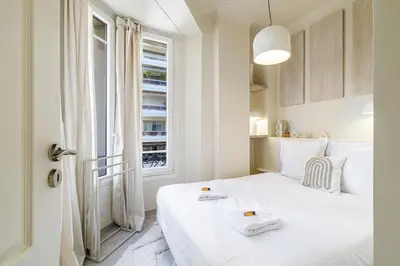 a white bedroom with a bed and a window at Cannes banana apartment in Cannes