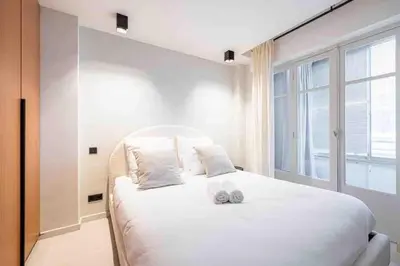 a bedroom with a large white bed with a window at Pasteur Luxury apartment la Croisette in Cannes