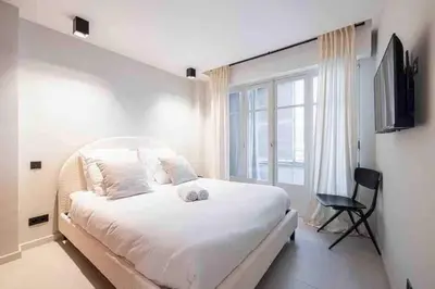 a bedroom with a large white bed and a window at Pasteur Luxury apartment la Croisette in Cannes