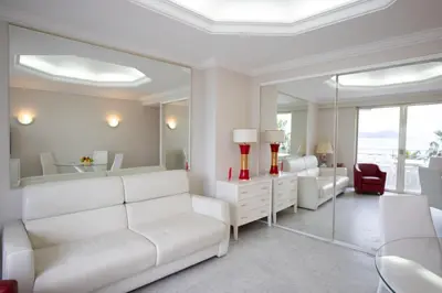 a living room with white furniture and a mirror at One bedroom apartment with beautiful sea view in Cannes