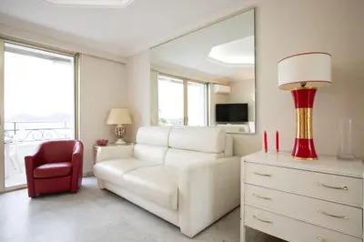 a living room with a white couch and a red chair at One bedroom apartment with beautiful sea view in Cannes