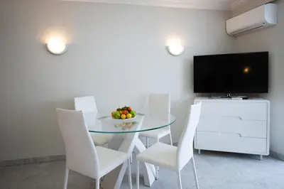 a dining room with a glass table and white chairs at One bedroom apartment with beautiful sea view in Cannes