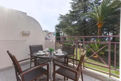 a table and chairs on a balcony with a palm tree at Cosy Francia - Terrasse, Piscine, parking, clim in Cannes