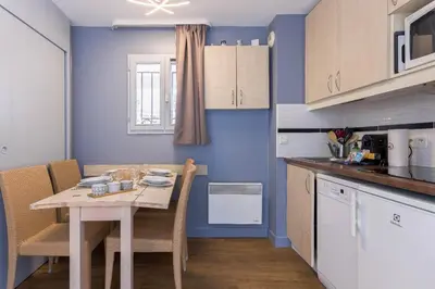 a kitchen with a table with chairs and a blue wall at Cosy Francia - Terrasse, Piscine, parking, clim in Cannes