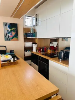 a kitchen with white cabinets and a wooden counter top at Appartement face mer LES PRINCES in Cannes