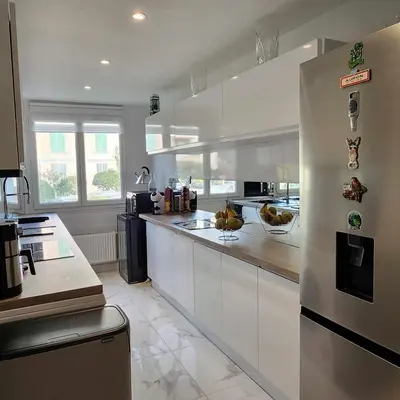 a kitchen with white cabinets and a stainless steel refrigerator at Victoria - Dr Picaud - 3 Pieces avec climatisation - 5 min des Plages in Cannes