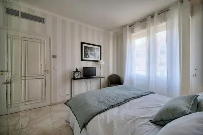 a white bedroom with a bed and a window at REF 1482 - Cannes Back Croisette - Apartment for rent in Cannes