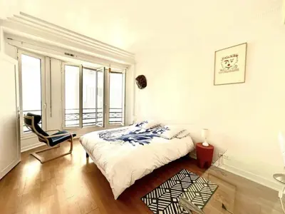 a bedroom with a bed and a chair and windows at Charming apartment steps away from La Croisette and Palais de Festival in Cannes