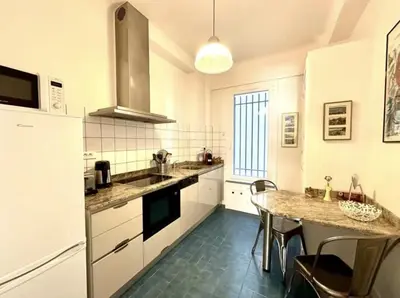 a kitchen with white cabinets and a table with chairs at Charming apartment steps away from La Croisette and Palais de Festival in Cannes