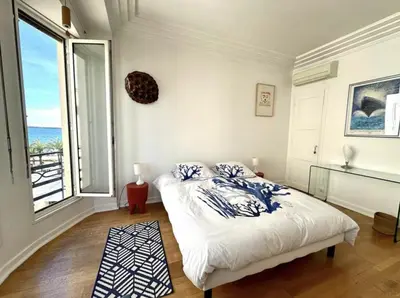 a bedroom with a bed and a large window at Charming apartment steps away from La Croisette and Palais de Festival in Cannes