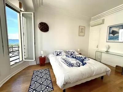a bedroom with a bed and a large window at Charming apartment steps away from La Croisette and Palais de Festival in Cannes