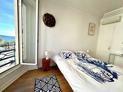 a bedroom with a bed and a large window at Charming apartment steps away from La Croisette and Palais de Festival in Cannes