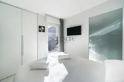 a white room with a bed and a window at 2 pièces - Très proche Croisette et Palais des Festivals in Cannes