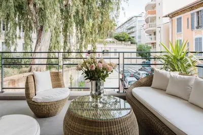 a balcony with a couch and chairs and a table with flowers at Luxueux appartement proche de la Croisette avec grande terrasse aménagée in Cannes