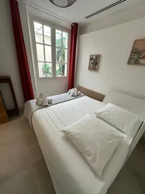 a white bed in a room with a window at Maison 4pièces -Haut Standing CANNES in Cannes