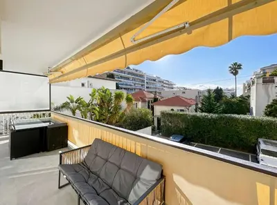 a couch sitting on a balcony with an umbrella at Appartement Moderne à Cannes in Cannes