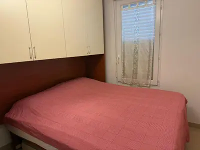 a bedroom with a bed with a red comforter and a window at Very bright T2 near beach in Cannes