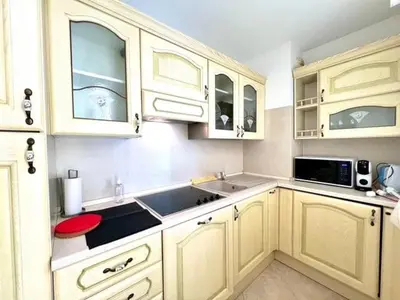 a kitchen with white cabinets and a sink and a microwave at Very bright T2 near beach in Cannes