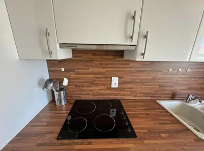 a kitchen with white cabinets and a black stove top at Cozy one bedroom apartment with balcony and parking in Cannes