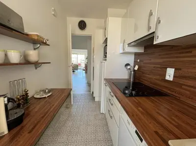 a kitchen with white cabinets and a wooden counter top at Cozy one bedroom apartment with balcony and parking in Cannes