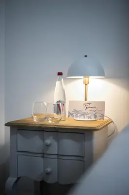 a table with two glasses and a bottle and a lamp at Jessicannes Hoche 4 min Palais Festival & Beaches in Cannes