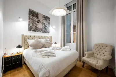 a bedroom with a large bed and a chair at Jessicannes Hoche 4 min Palais Festival & Beaches in Cannes