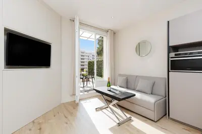 a living room with a couch and a tv at Palais Miramar YourHostHelper in Cannes