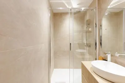 a bathroom with a glass shower and a sink at Palais Miramar YourHostHelper in Cannes