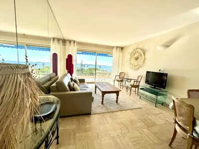 a living room with a couch and a table at Reflets d'Azur - Vue mer, plage, neuf, moderne in Cannes