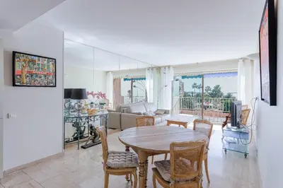 a living room with a wooden table and chairs at Reflets d'Azur - Vue mer, plage, neuf, moderne in Cannes