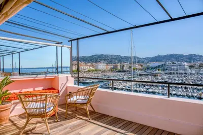 a balcony with chairs and a view of a harbor at REF 1923 - Cannes Vieux-Port 5-star penthouse for rent sea view in Cannes
