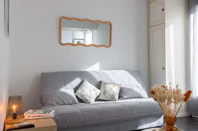 a gray couch in a living room with a mirror at Rue Hoche by Halldis in Cannes