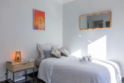 a bedroom with a bed and a side table with a mirror at Rue Hoche by Halldis in Cannes
