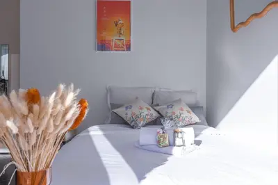 a white bed with pillows and a vase with flowers at Rue Hoche by Halldis in Cannes