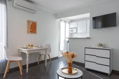 a white kitchen with a table and a table and chairs at Rue Hoche by Halldis in Cannes