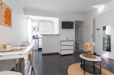 a white kitchen with a table and a counter at Rue Hoche by Halldis in Cannes