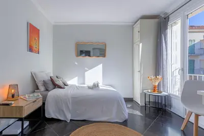 a white bedroom with a bed and a couch at Rue Hoche by Halldis in Cannes