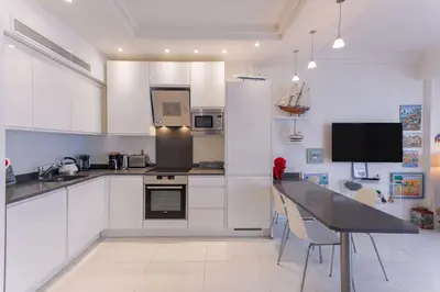 a kitchen with white cabinets and a black counter top at Palais Des Iles 2 by Halldis in Cannes